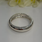Silver bangle on a white surface with yellow flowers in the background