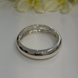 Silver bangle on a white surface with yellow flowers in the background