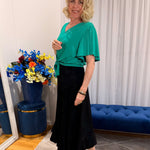 Woman wearing green top and black skirt