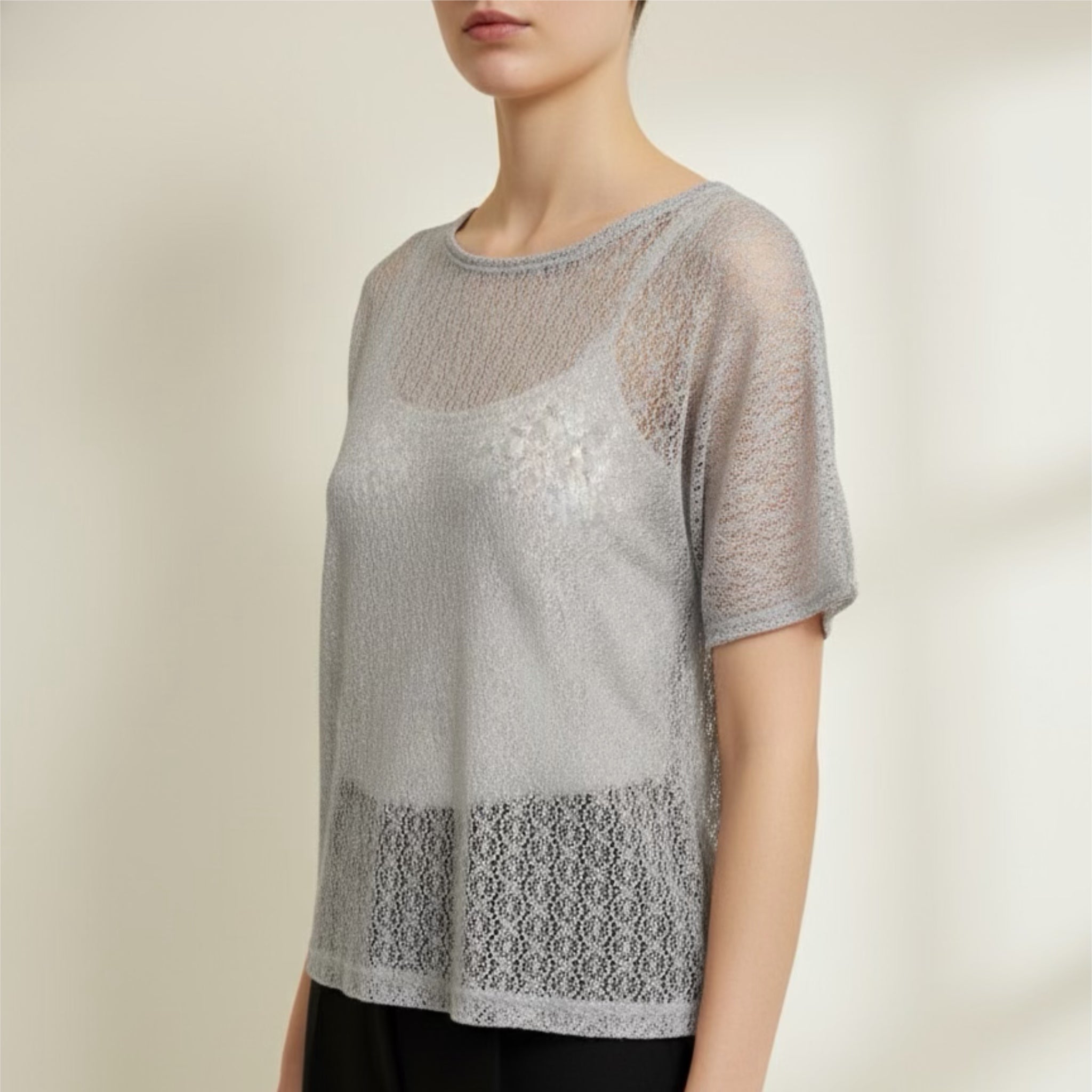 Woman wearing a sheer top with lace details on a plain background