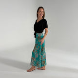 Woman wearing a black top and teal patterned skirt on a white background