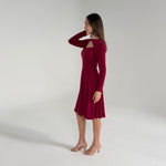 Woman wearing a burgundy dress with long sleeves on a white background