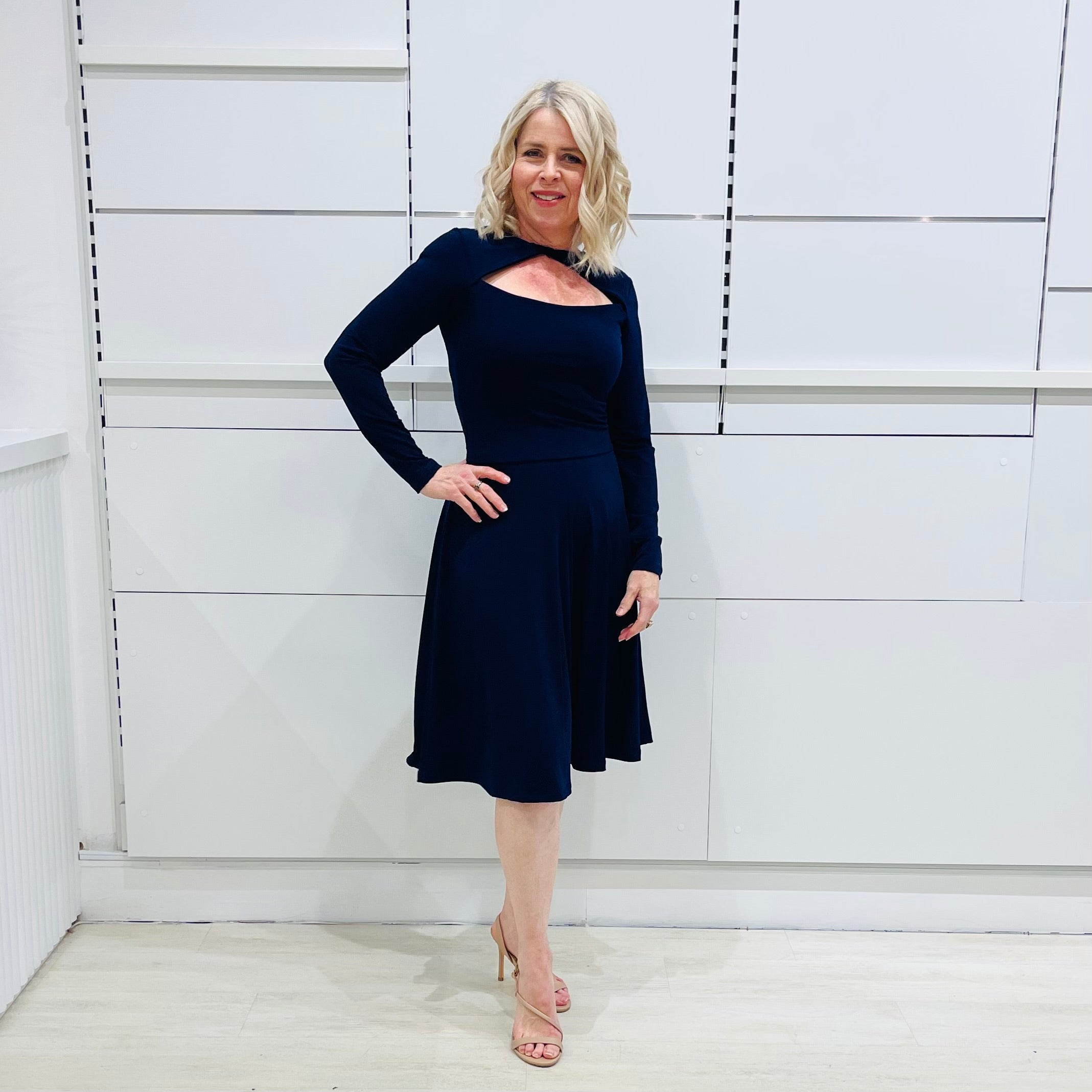 Penelope dress in deep navy blue, worn by model- elegant long sleeve design, knee length, with modern neckline.