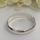 Silver bracelet on a white surface with yellow flowers in the background
