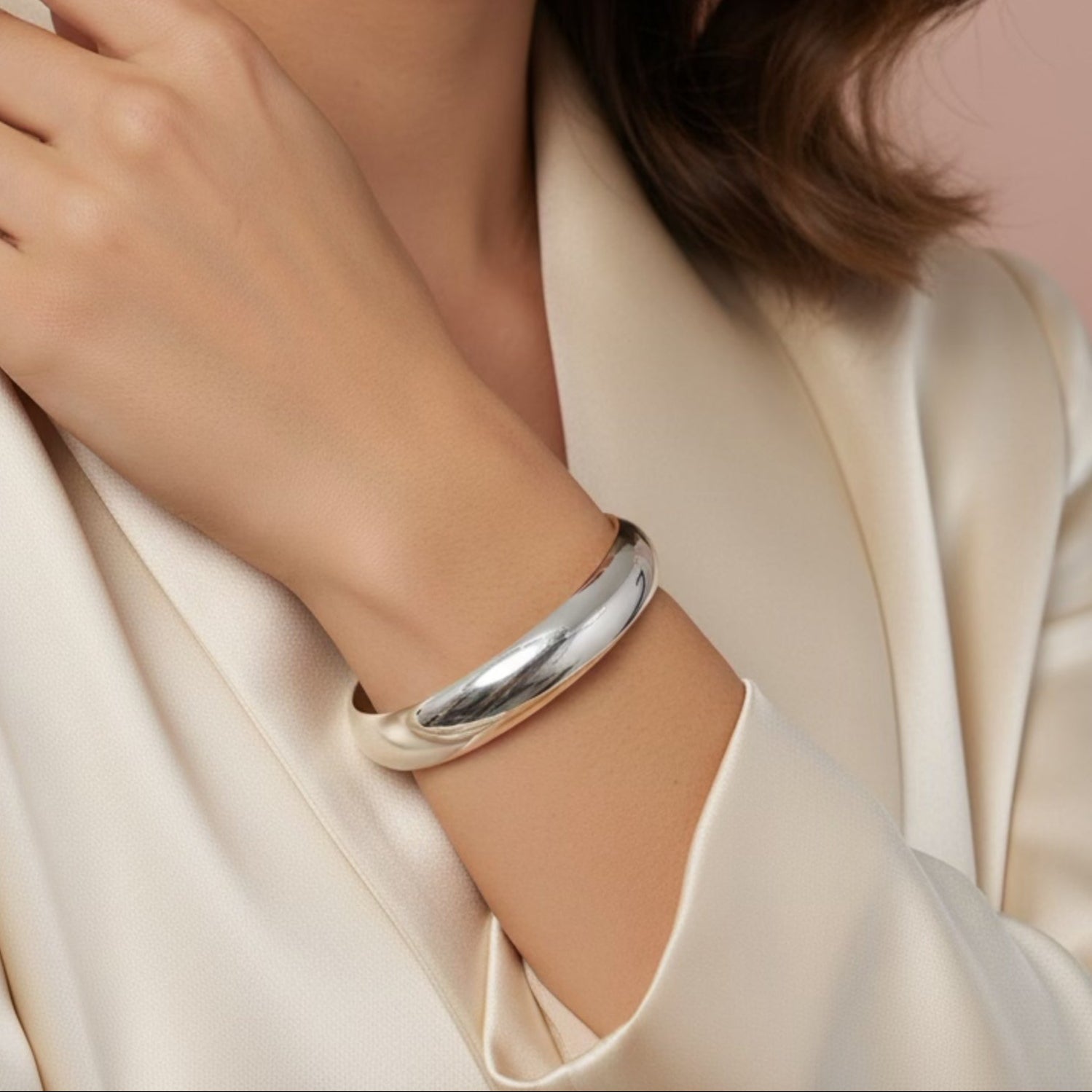 Close-up of a woman wearing a silver bracelet on a beige background