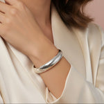 Close-up of a woman wearing a silver bracelet on a beige background