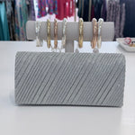Silver clutch bag with jewelry on a white surface
