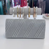 Silver clutch bag with jewelry on a white surface