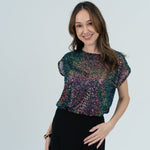 Woman in glitter top in  white room 