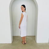 Woman wearing a white dress standing in a minimalistic setting with a white archway.