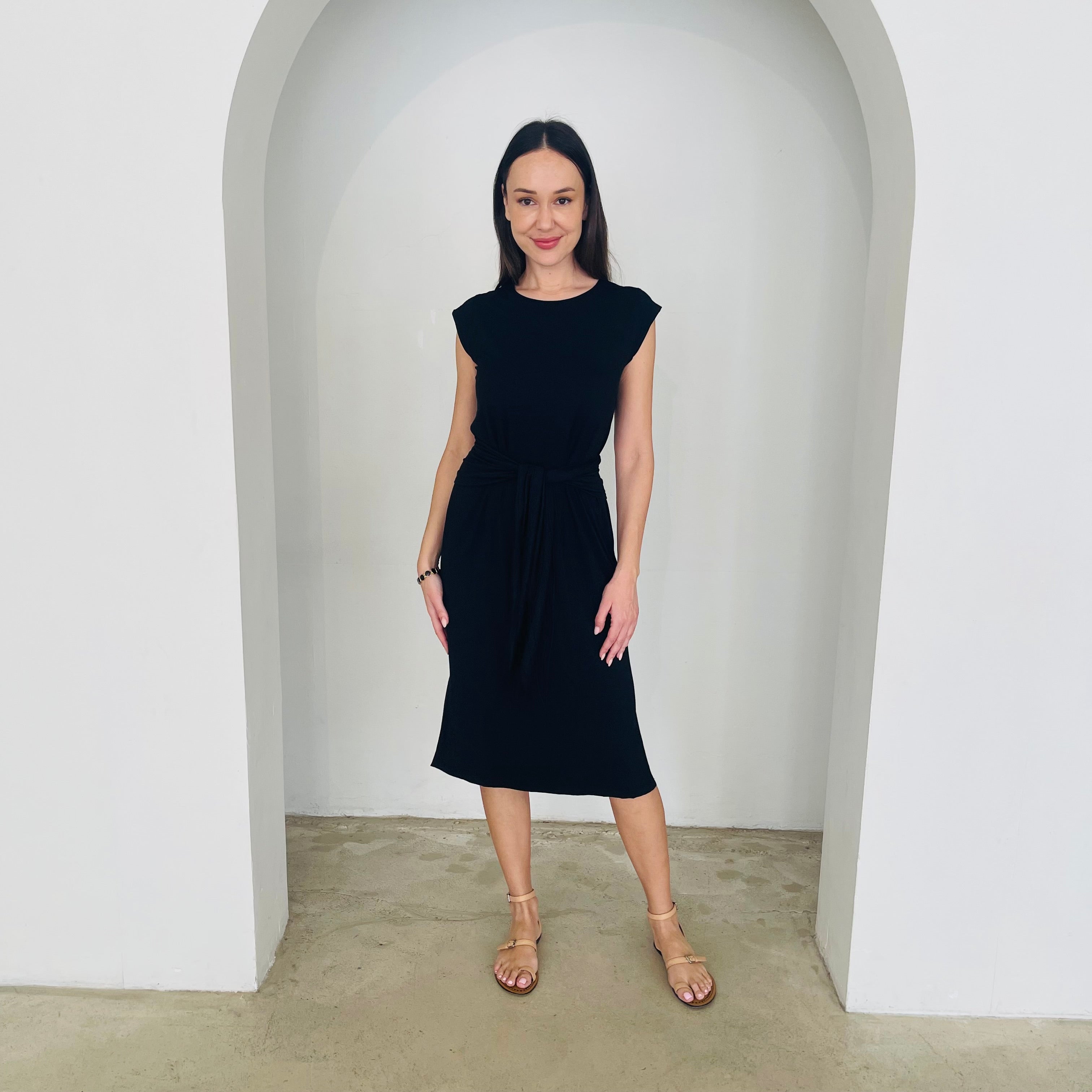 Woman wearing a black dress standing in a white archway.
