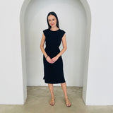 Woman wearing a black dress standing in a white archway