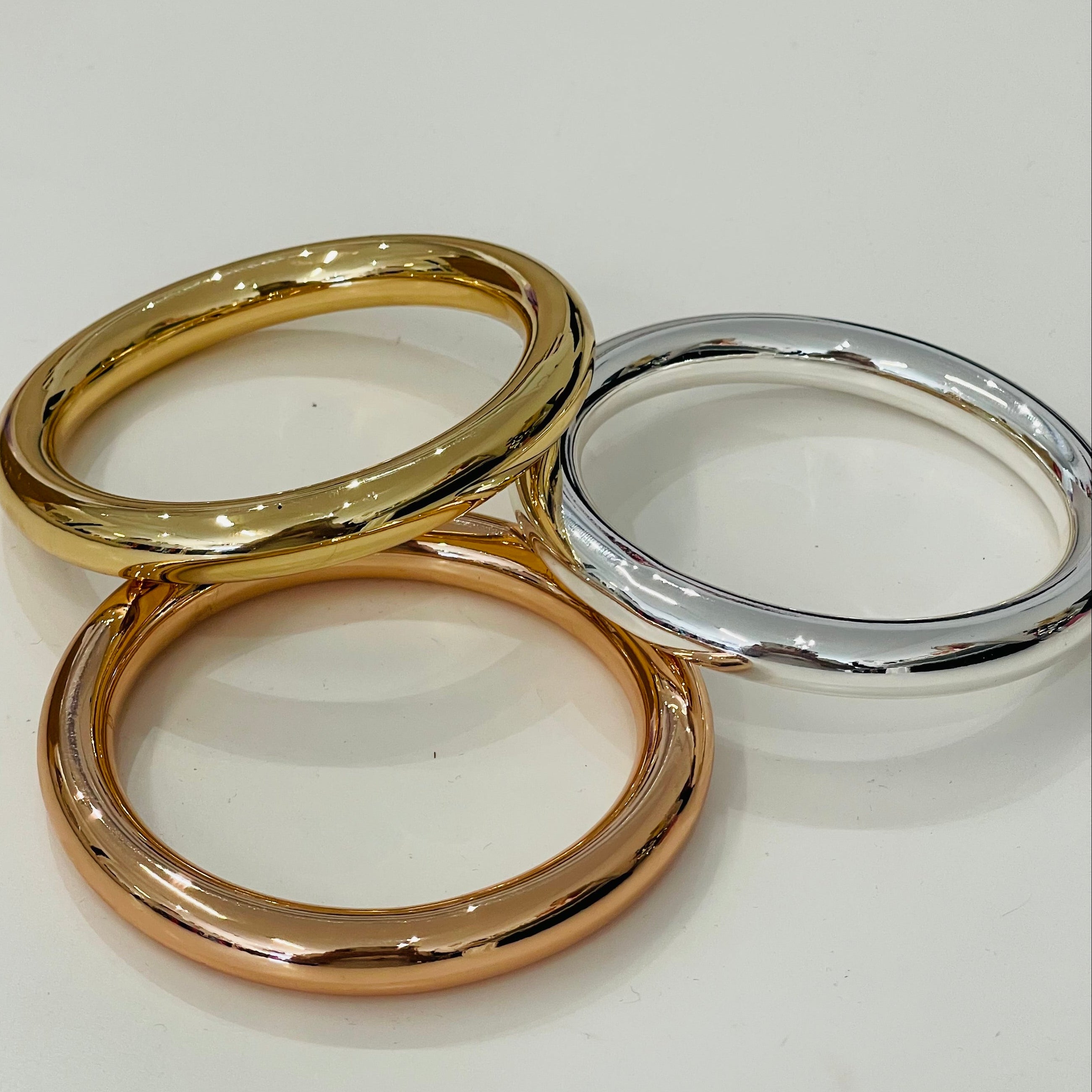 Three bracelets  in gold, rose gold, and silver on a white background