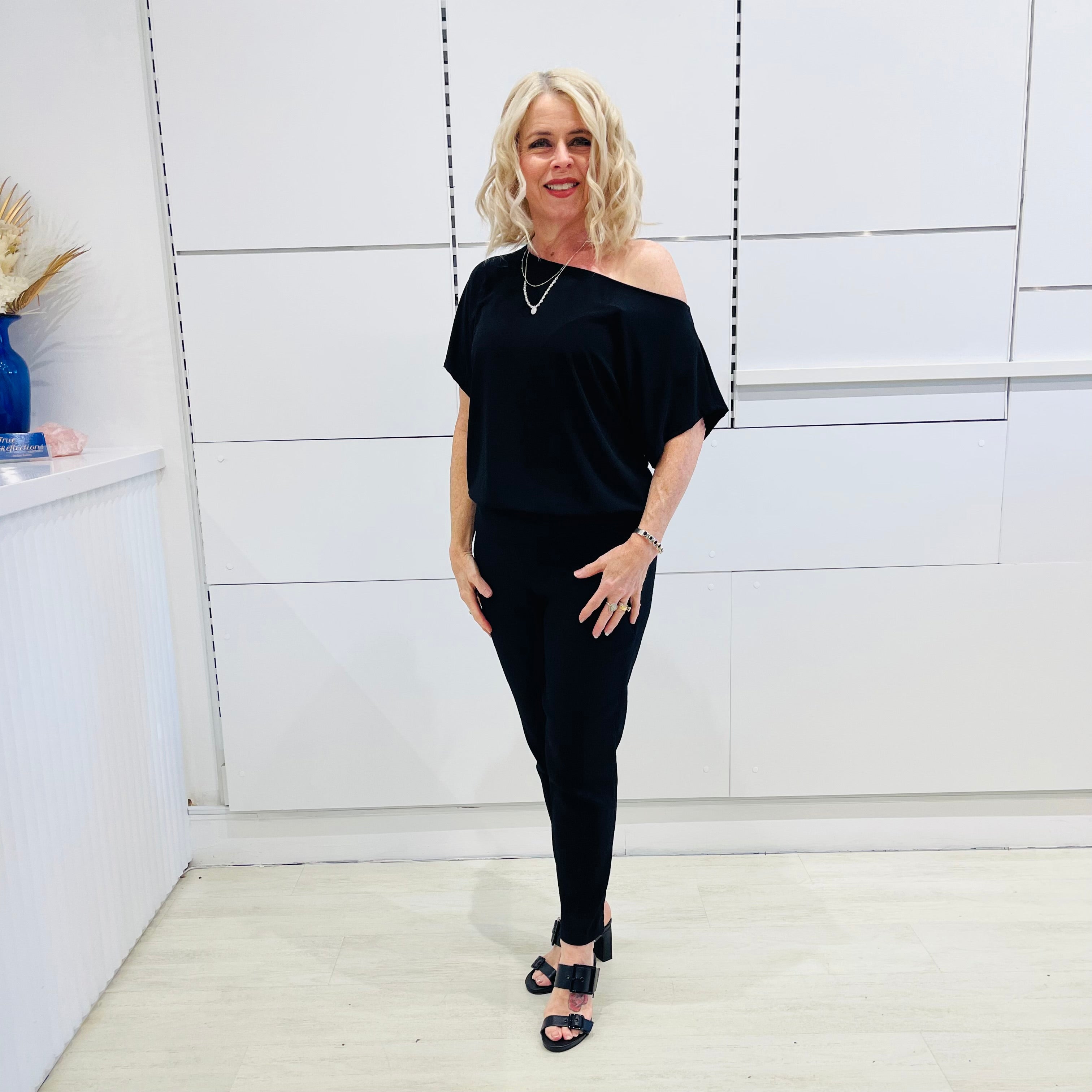 Black, textured fabric with subtle  Jaguar design pattern,  tapered leg pant with, pockets, stretch waistband, side seam invisible zipper opening. Black off the shoulder top.