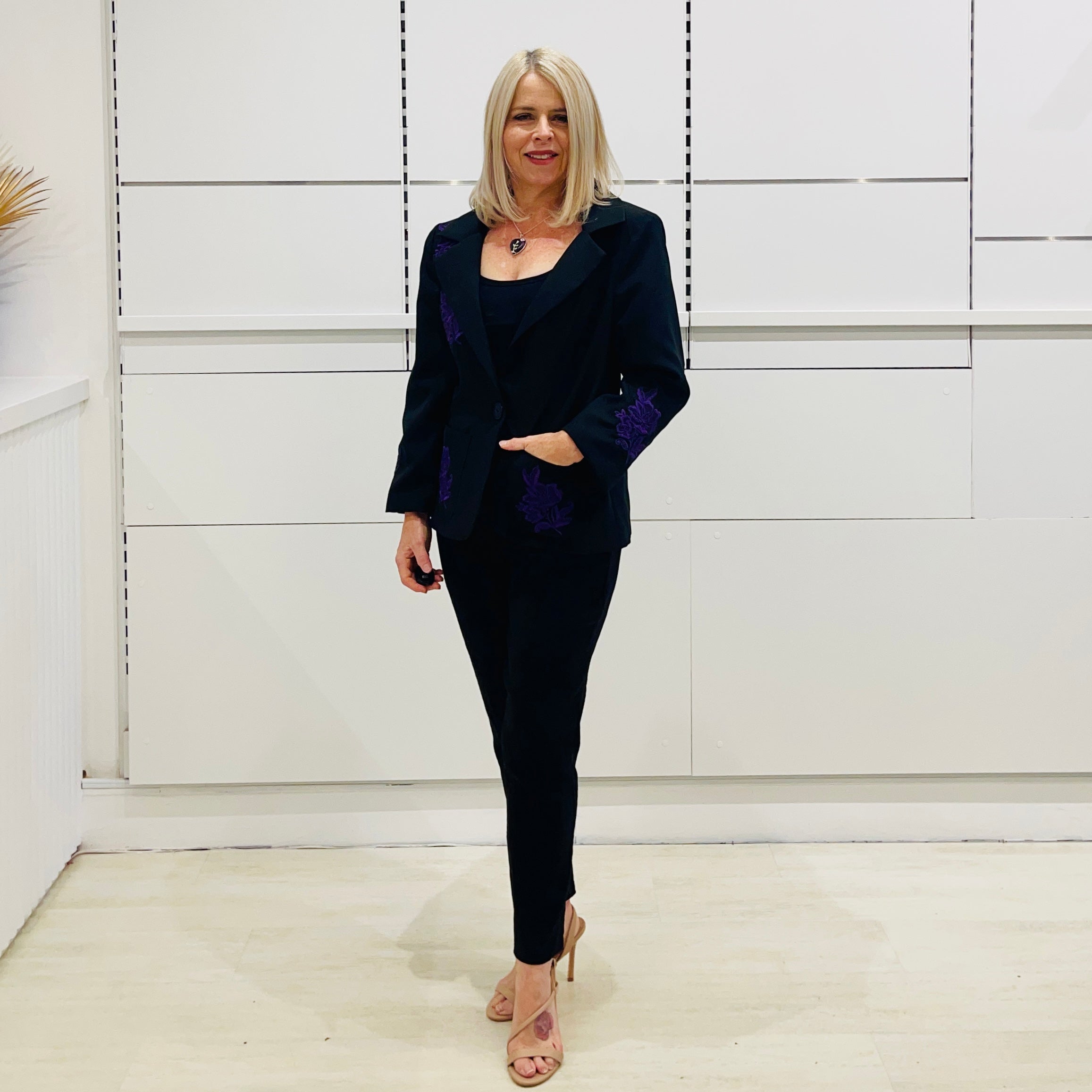 Sophisticated black blazer, jacket, with traditional one button closure style and fit, purple embroidered highlight motifs on front, back, sleeves and pockets.