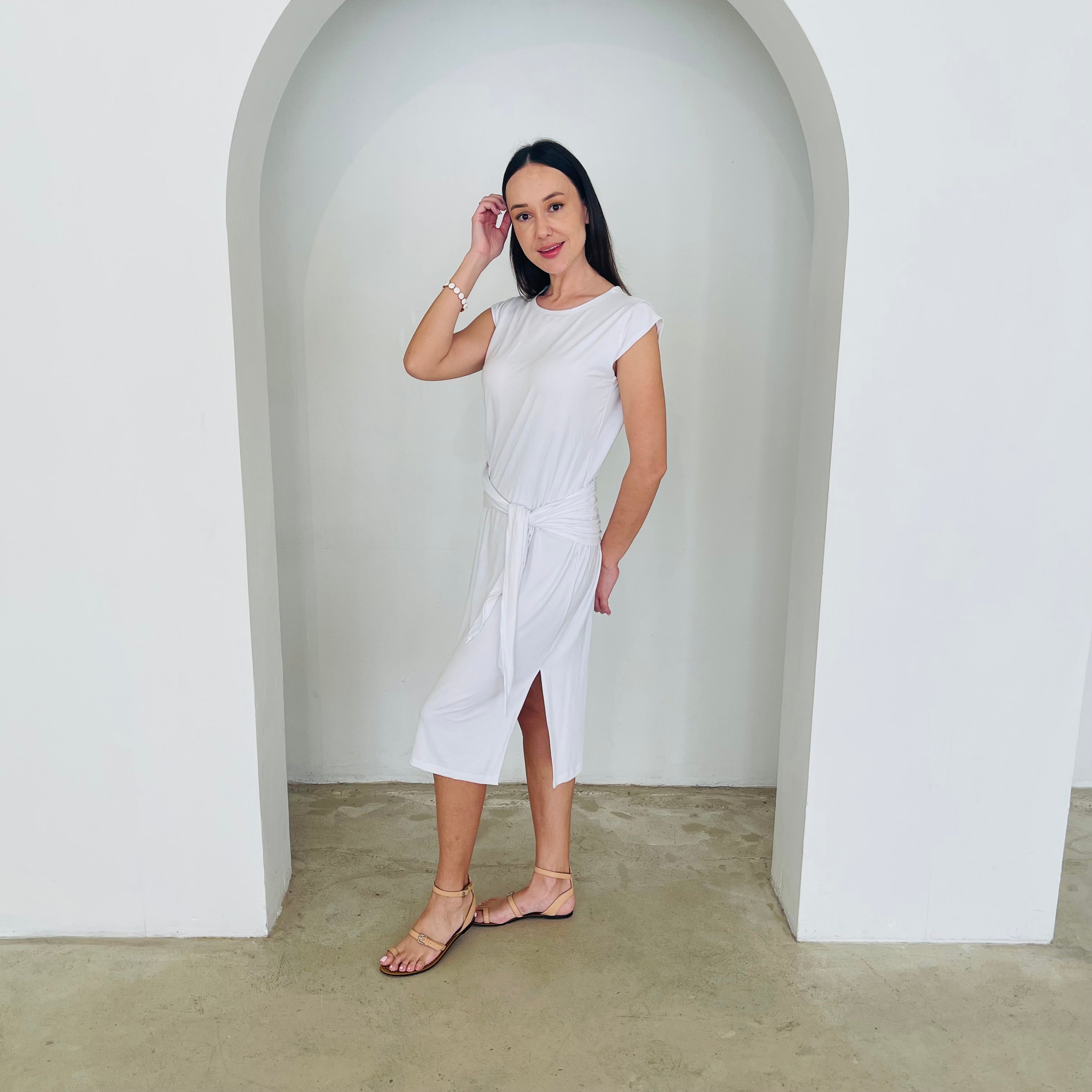 Woman in a white dress standing in a minimalistic setting with a white archway.