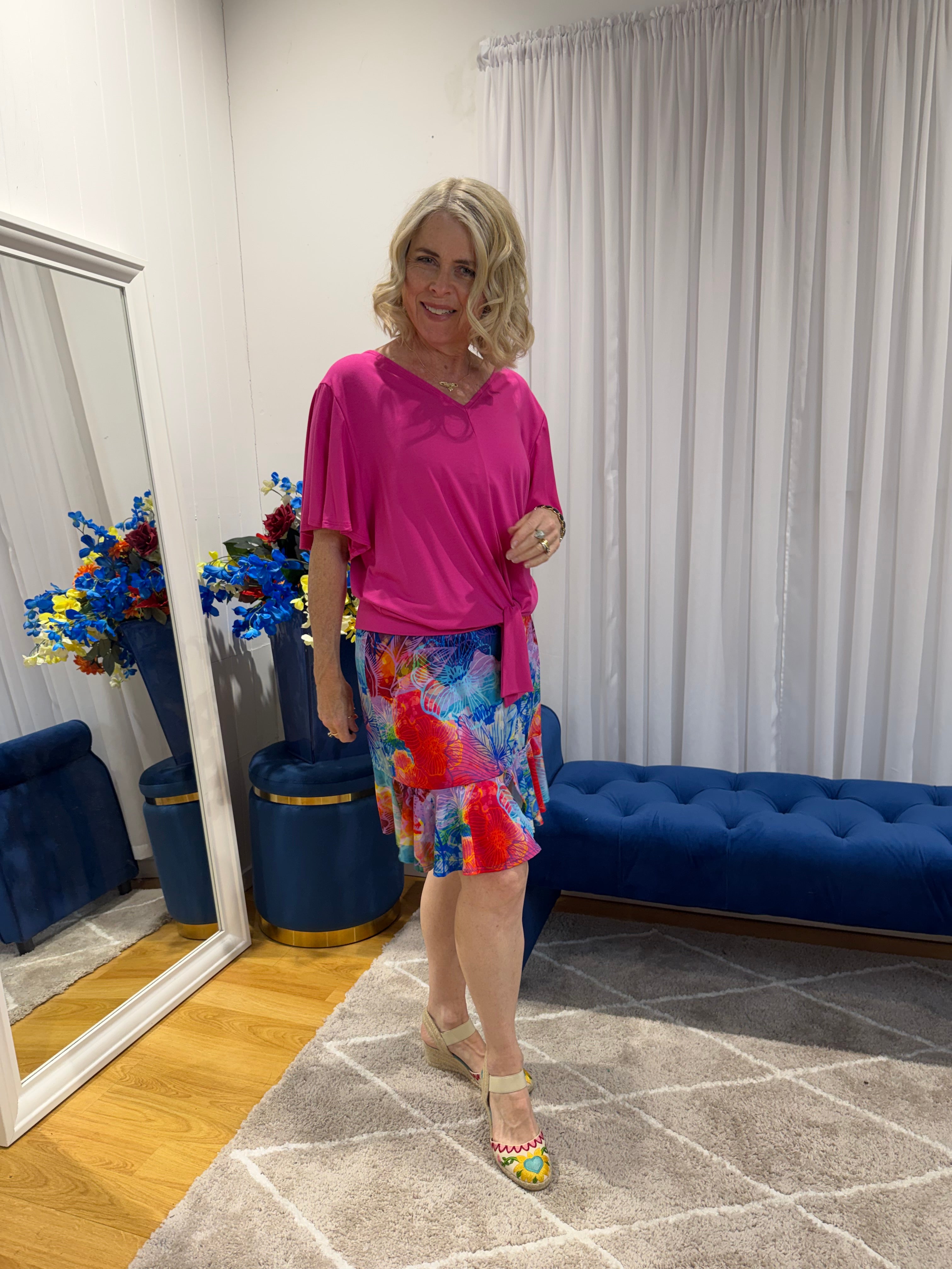 Woman wearing pink top and short colourful skirt 