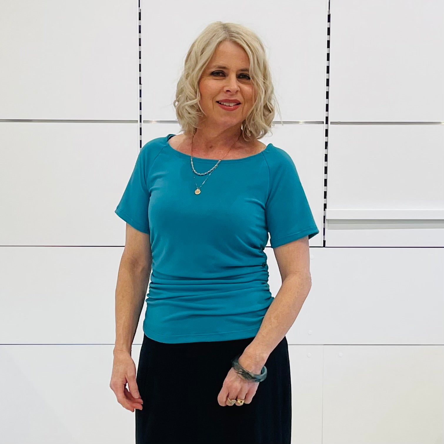 Woman wearing a blue top and black skirt against a white background