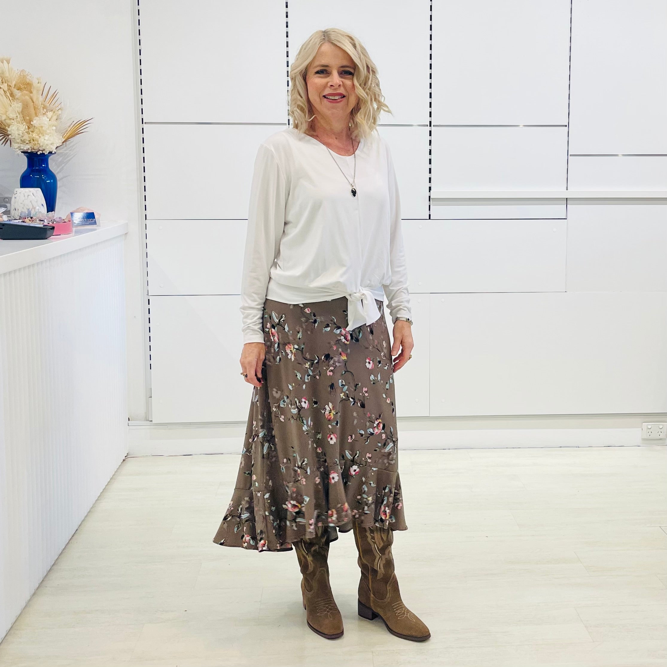 White long sleeve, v neckline, top with waist tie front, worn with floral, midi length skirt.