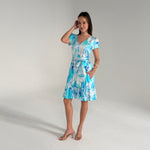 Woman wearing a blue and white patterned dress on a gray background