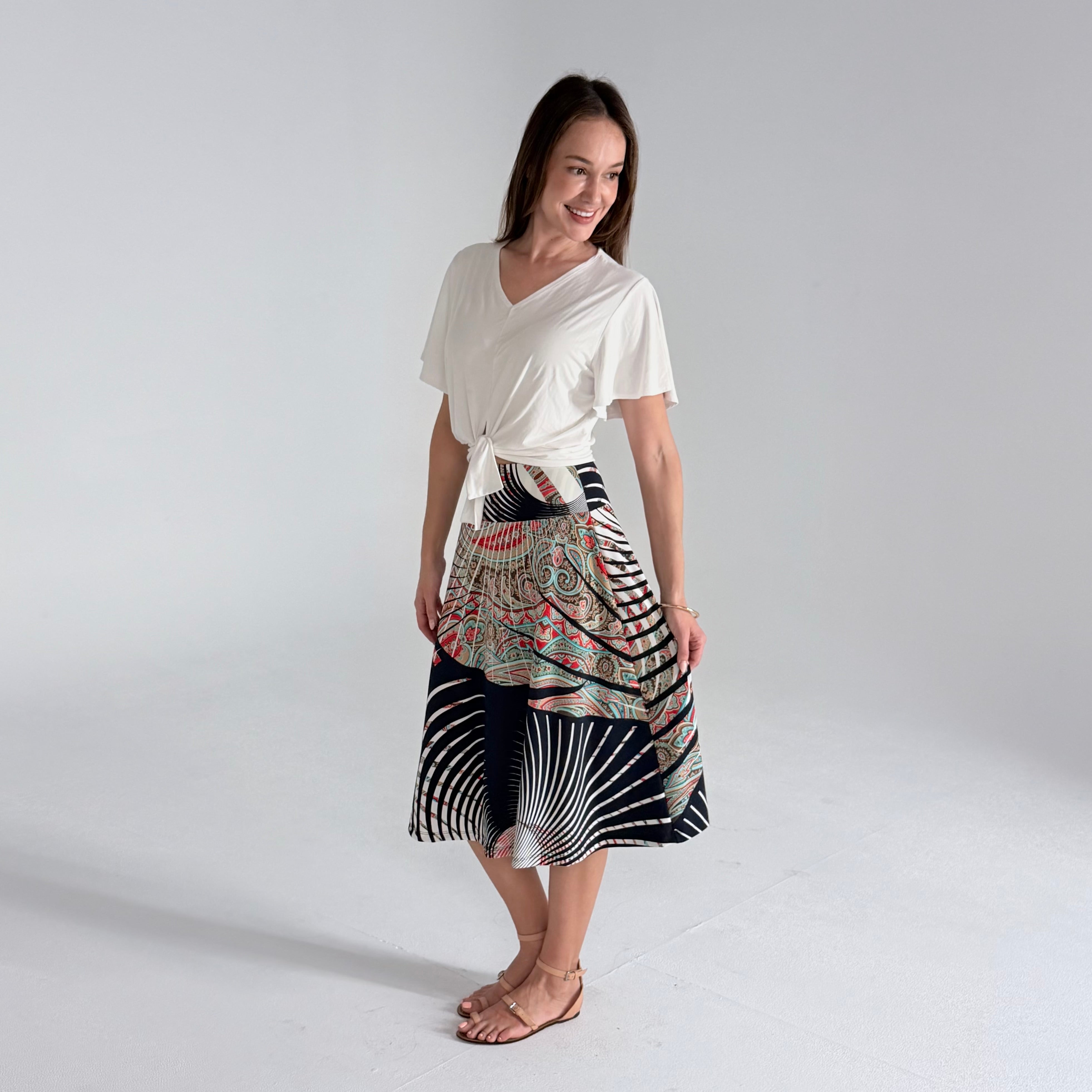 Woman wearing a white top and patterned skirt on a plain background