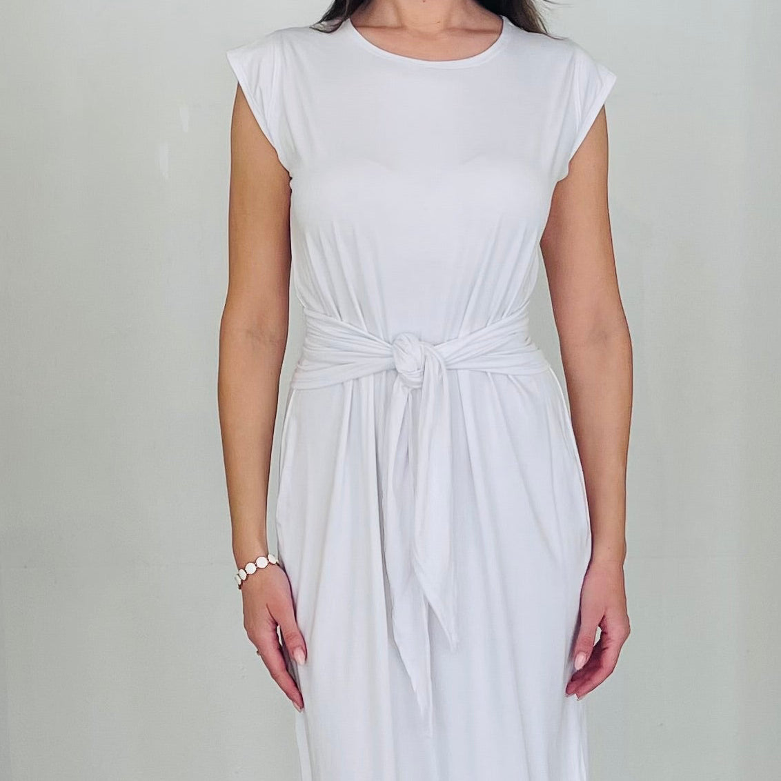 Woman in a white dress standing in a white archway.