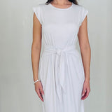 Woman in a white dress standing in a white archway.