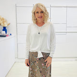 White long sleeve, v neckline, top with waist tie front, worn with floral, midi length skirt.