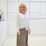 White long sleeve, v neckline, top with waist tie front, worn with floral, midi length skirt.