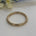 Gold bracelet bangle on a white surface with flowers in the background