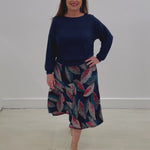 Introducing our Navy Bamboo Blend Gracie Top. Versatile relaxed fit: wear on the waist, on the hips or lengthen for more coverage. The slight drop shoulder design allows ample room around the bust and arms. The cuffed wrist allows varied sleeve length options. The bamboo blend is breathable, soft and comfortable. Paired with our Autumn Radiance Aline Midi length skirt. In a stretch jersey fabric with a teal, red, white, navy and black leaf print.